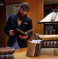 Photo, taken in the Rare Books reading room, of Myron Groover looking at an old book. Courtesty of Myron Groover.